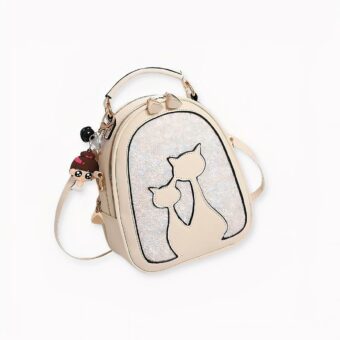 Mochila de purpurina en polipiel con un estampado en forma de dos gatos. Un colgante de niña cuelga de la cremallera. Nuestra mochila está disponible en una gama de colores para combinar con sus deseos más salvajes. Demasiado mona, ¡esta pequeña mochila gustará por igual a las niñas y a las mujeres amantes de los gatos!