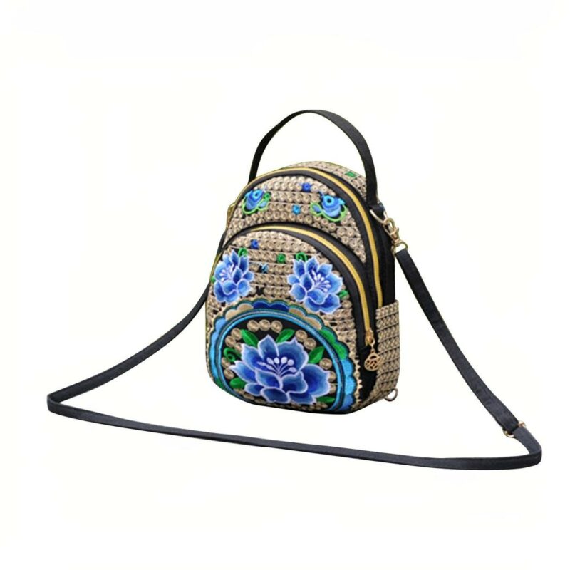 Mochila vintage bordada en marrón con detalles de flores azules y fondo blanco