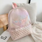 Mochila de niña sirena rosa con almohada sobre una cama en una casa