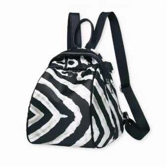 Mochila pequeña de mujer en tejido con estampado de cebra sobre fondo gris claro.