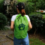 Bolsa de playa de malla verde con fondo de jardín y mujer llevando la bolsa
