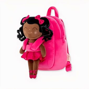 mochila infantil de primer grado, rosa con un muñeco de peluche de una niña vestida de bailarina de ballet en la parte delantera. Es una joven de color, sonriente y con los ojos cerrados.