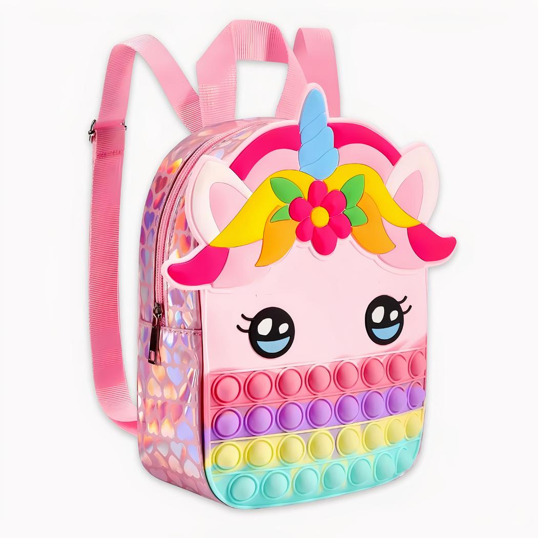 Foto de una mochila rosa con cabeza de unicornio. El contorno de la mochila es brillante y en el fondo tiene colores rosa, morado, amarillo y azul pop it. En el centro están sus ojos y sobre ellos sus orejas con una melena en forma de frutas y flores, y luego su cuerno que es azul. El fondo es gris claro.