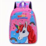 Foto de una mochila de unicornio. Es rosa, con nubes azules, arco iris, estrellas y pequeñas nubes. El unicornio es blanco con un cuerno del color del arco iris y una melena roja. Sobre ella está escrito Dulces sueños en multicolor.