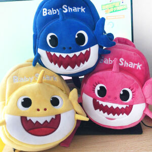 3 mochilas de felpa para niños que representan un simpático tiburón. Esta se coloca sobre una mesa plana